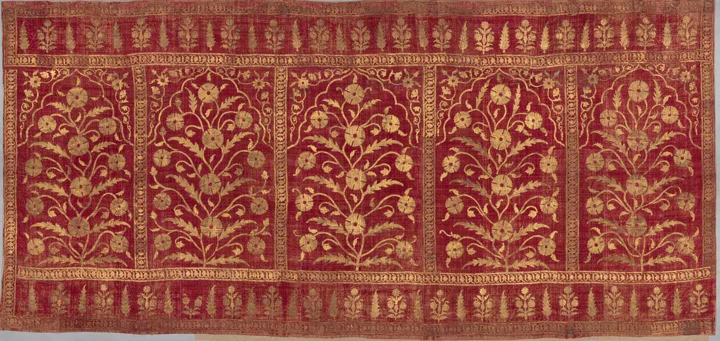 A crimson velvet tent panel with gold flowering plants under five cusped arches