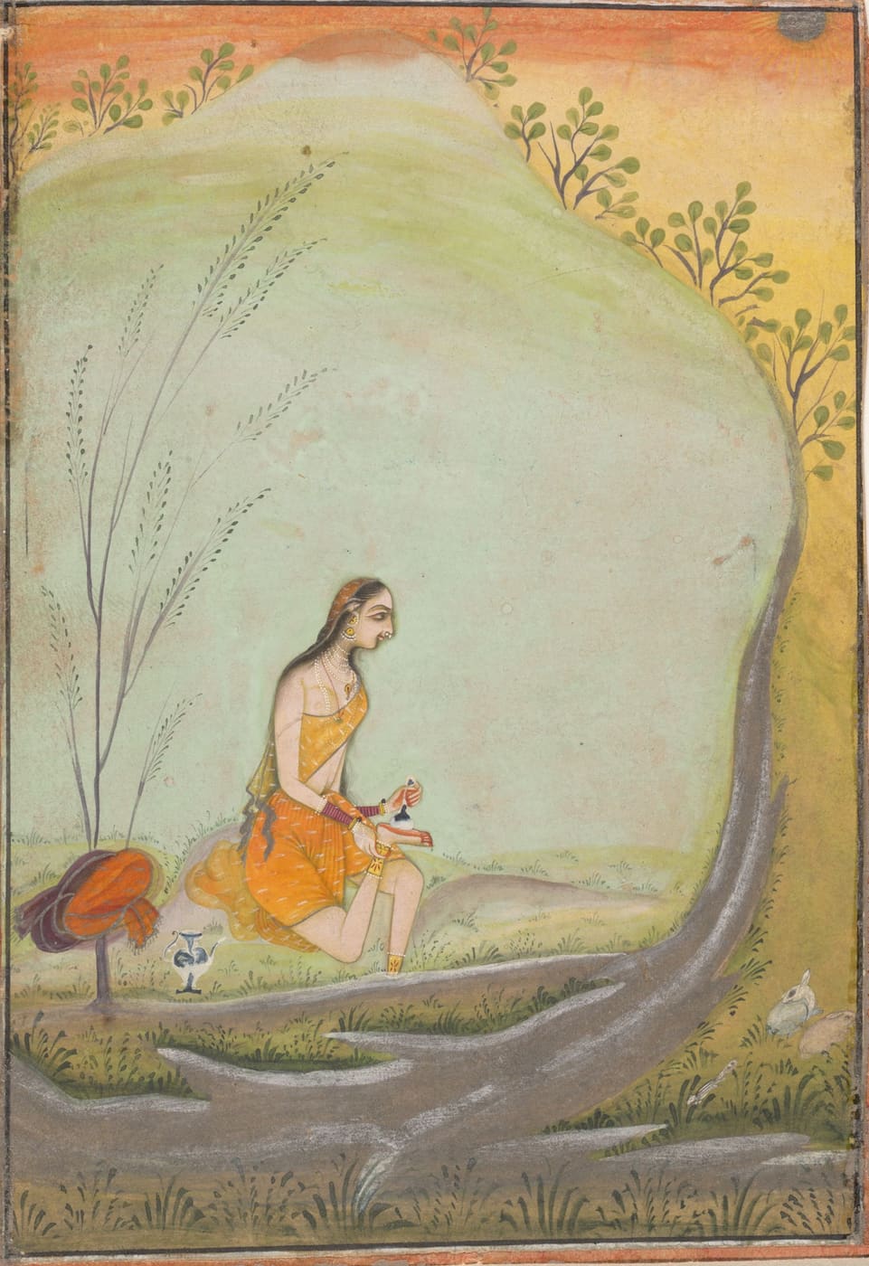 A lady seated under a tree applies henna to her foot