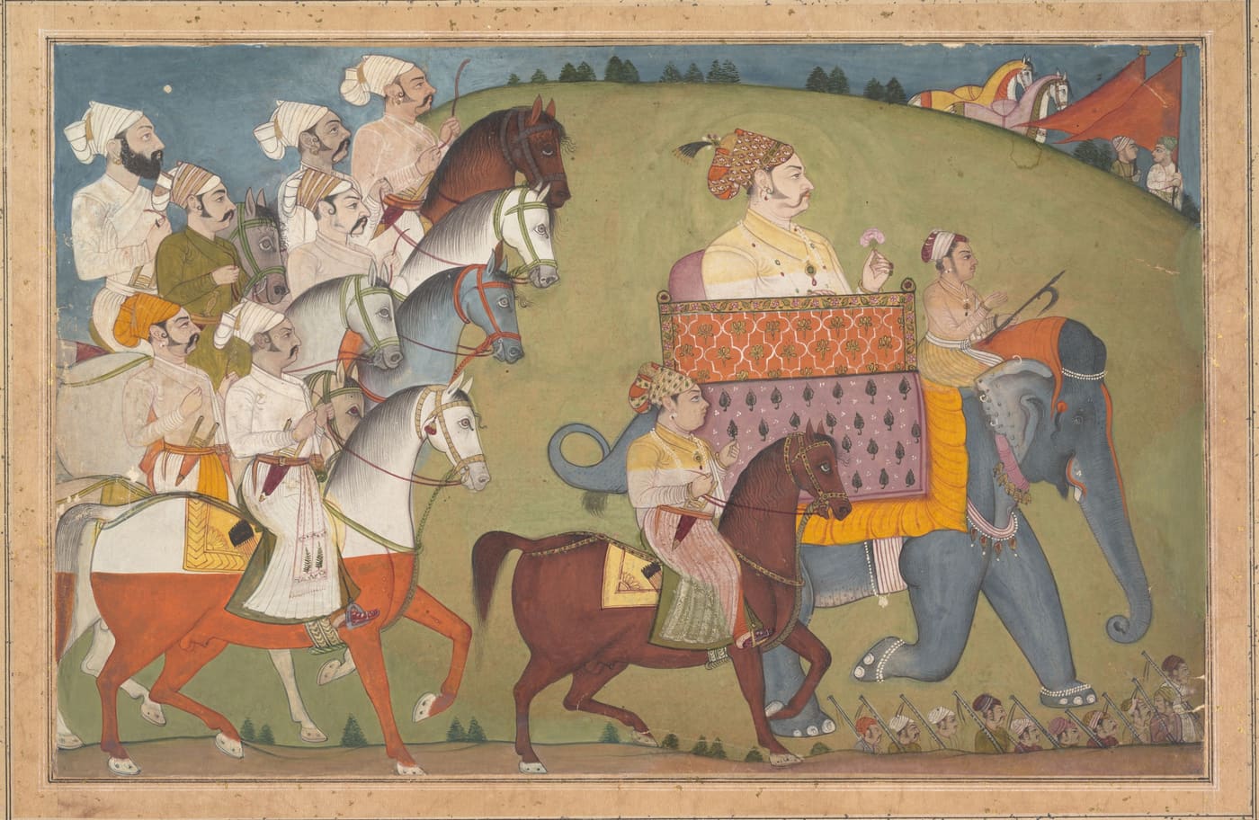 A maharaja on an elephant rides in procession with horsemen